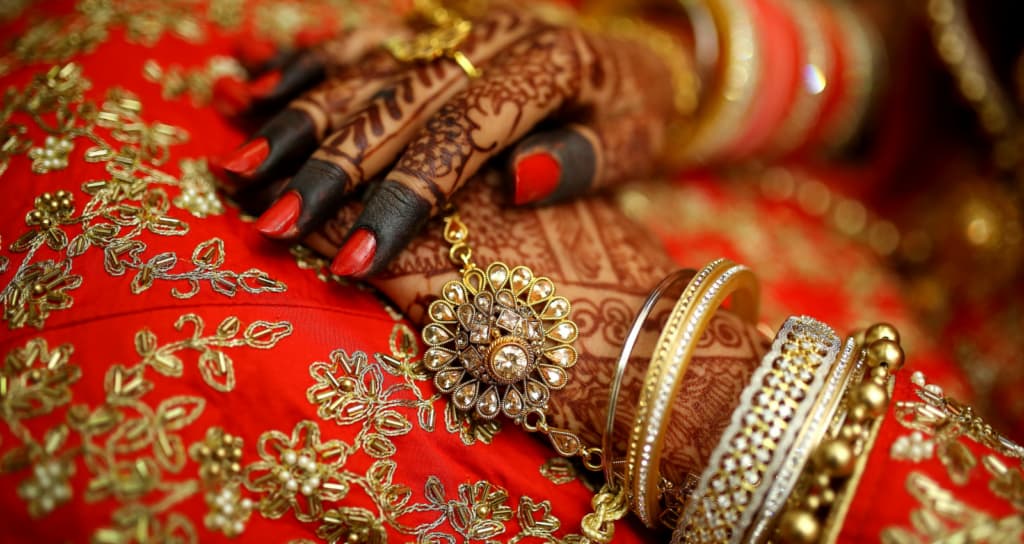 Image of hands gold jewellery, red finger nails